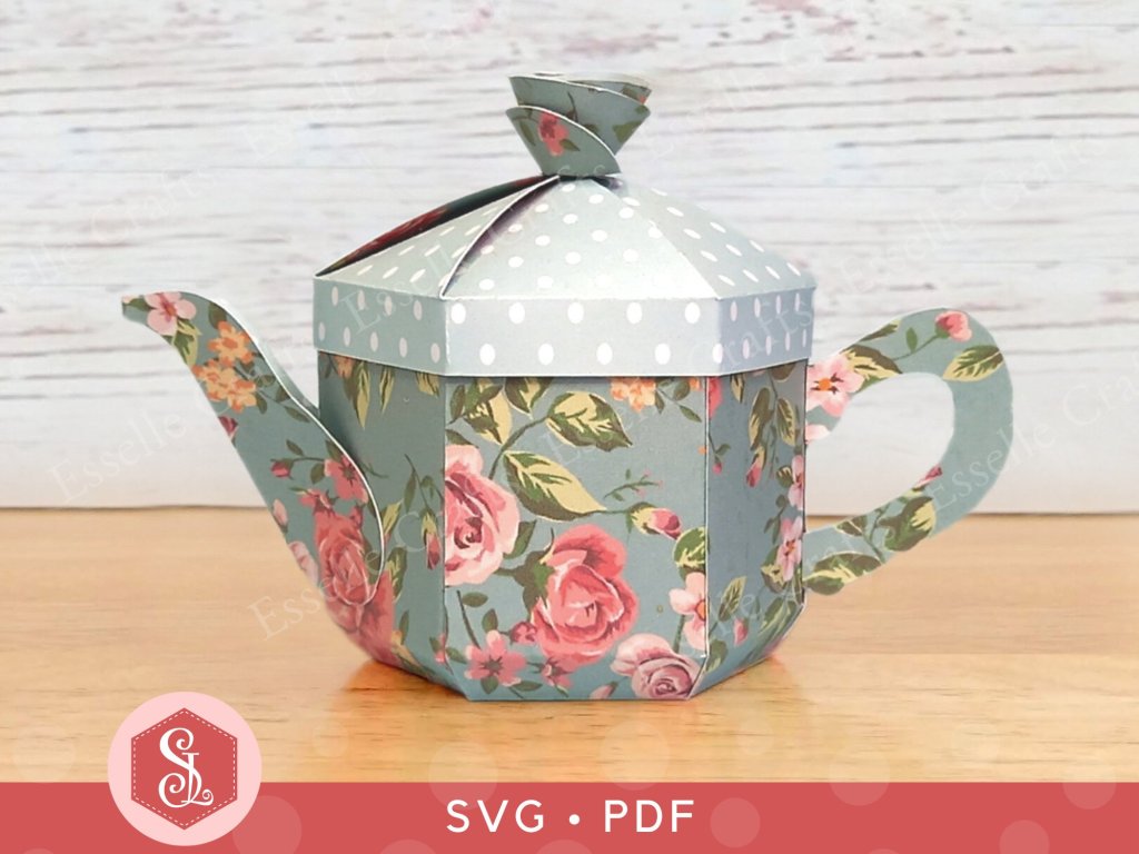 A blue papercraft teapot gift box decorated with pink roses and white spots on the lid