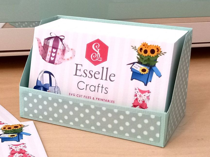 A business card display box made from mint green cardstock and decorated with white spotty card on a desk holding 100 business cards.