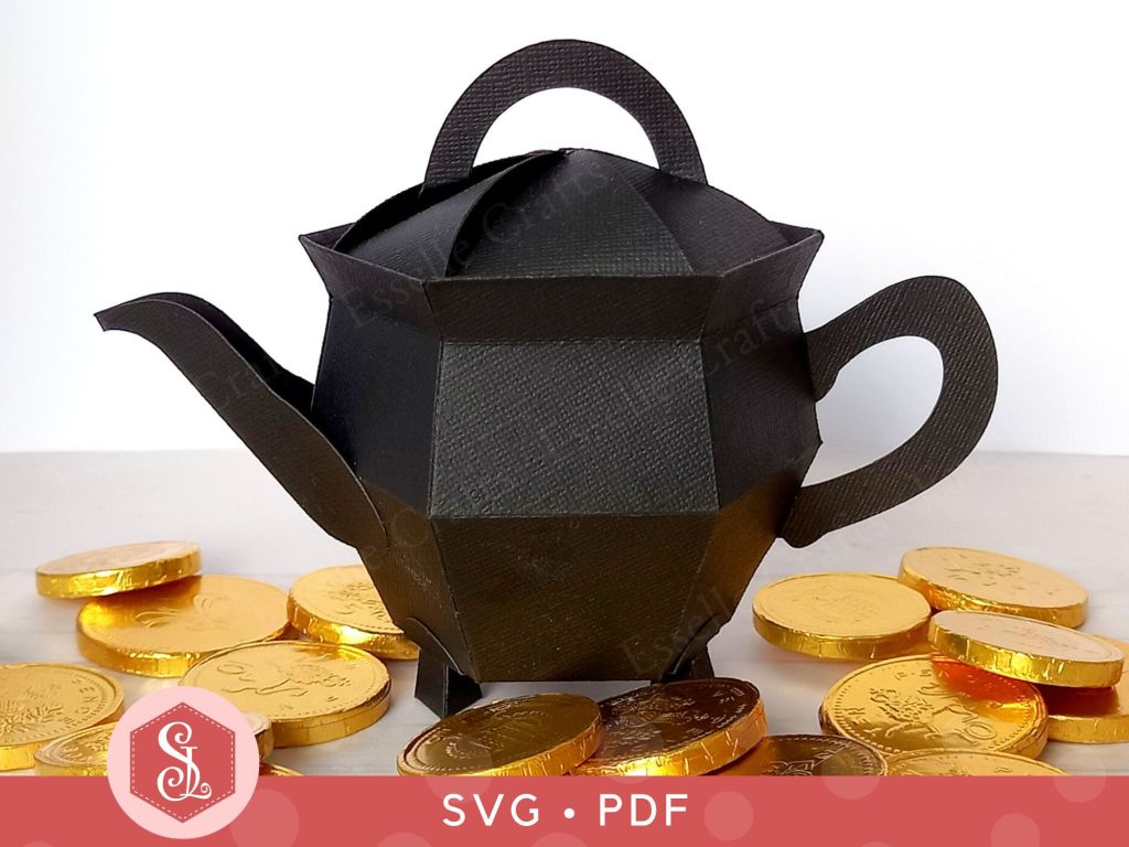 An impressive black papercraft teapot gift box in the shape of a witch cauldron surrounded by gold chocolate coins.