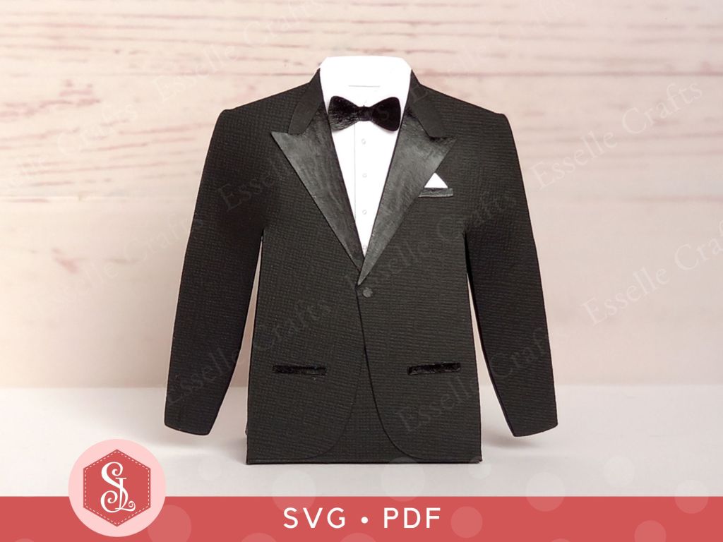 A black paper craft tuxedo favour box with a white shirt a black satin paper bow tie and a white handkerchief in the top pocket