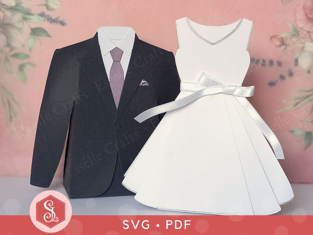 A dark grey paper craft suit jacket favour box with a white shirt a light purple tie and matching handkerchief in the top pocket and a white papercraft dress favour box with a pretty white satin bow at the waist