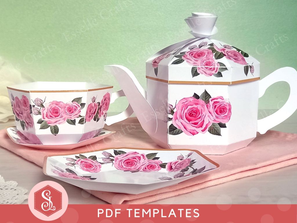 A white papercraft tea set consisting of a teapot gift box paper teacup and saucer and tea plate all decorated with a pink rose design