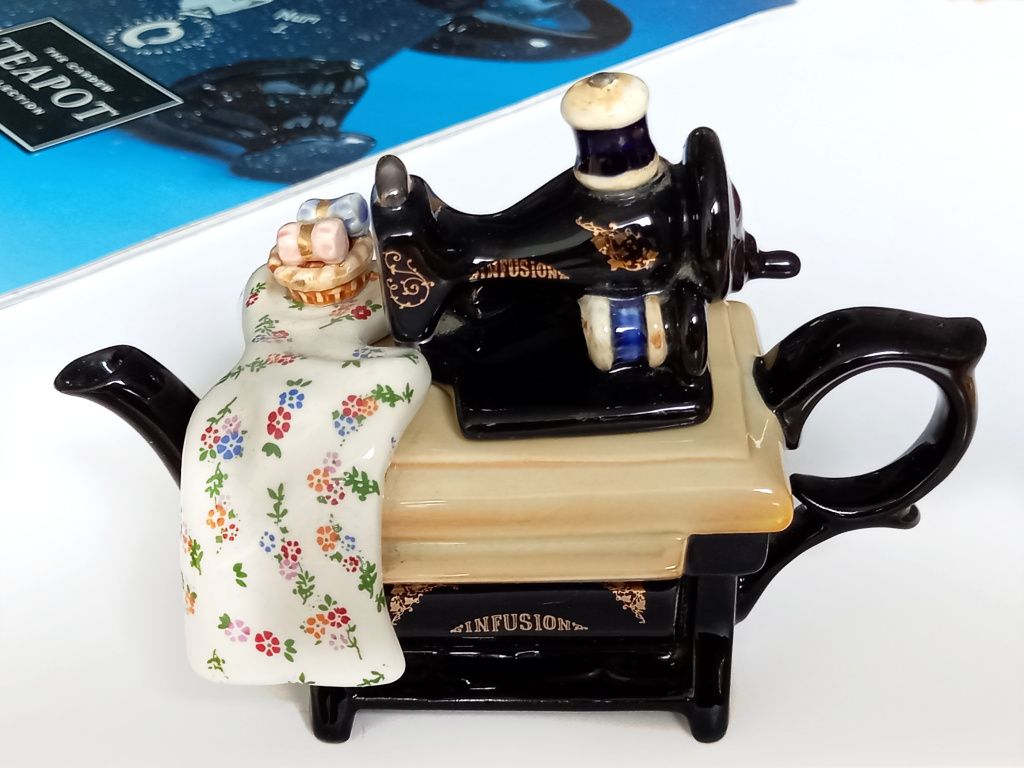 A one cup novelty teapot designed to look like a Singer sewing machine stand with a small black sewing machine as the teapot lid