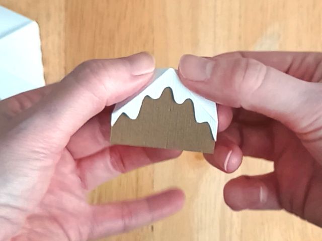 Making part of a brown paper craft teapot gift box in the style of a classic gingerbread house