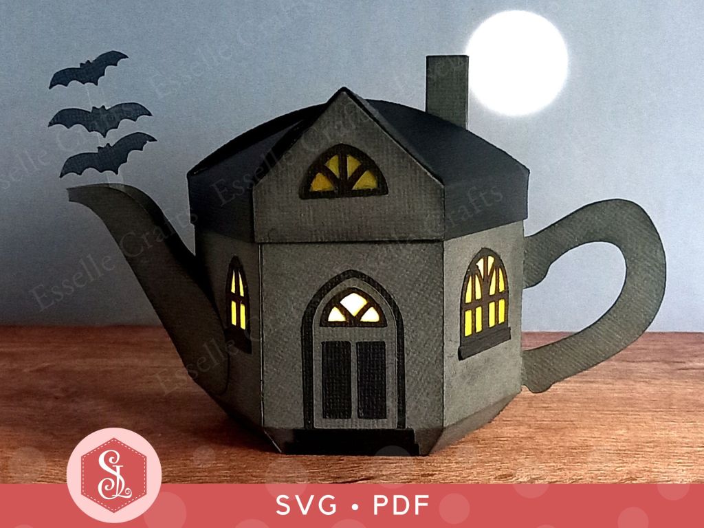 A paper craft haunted house gift box for Halloween trick or treating in the shape of a teapot with yellow arched gothic windows and three bats flying out of the spout