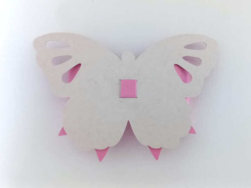 A pink butterfly bow made from textured cardstock that can be used on gift packaging or home decor