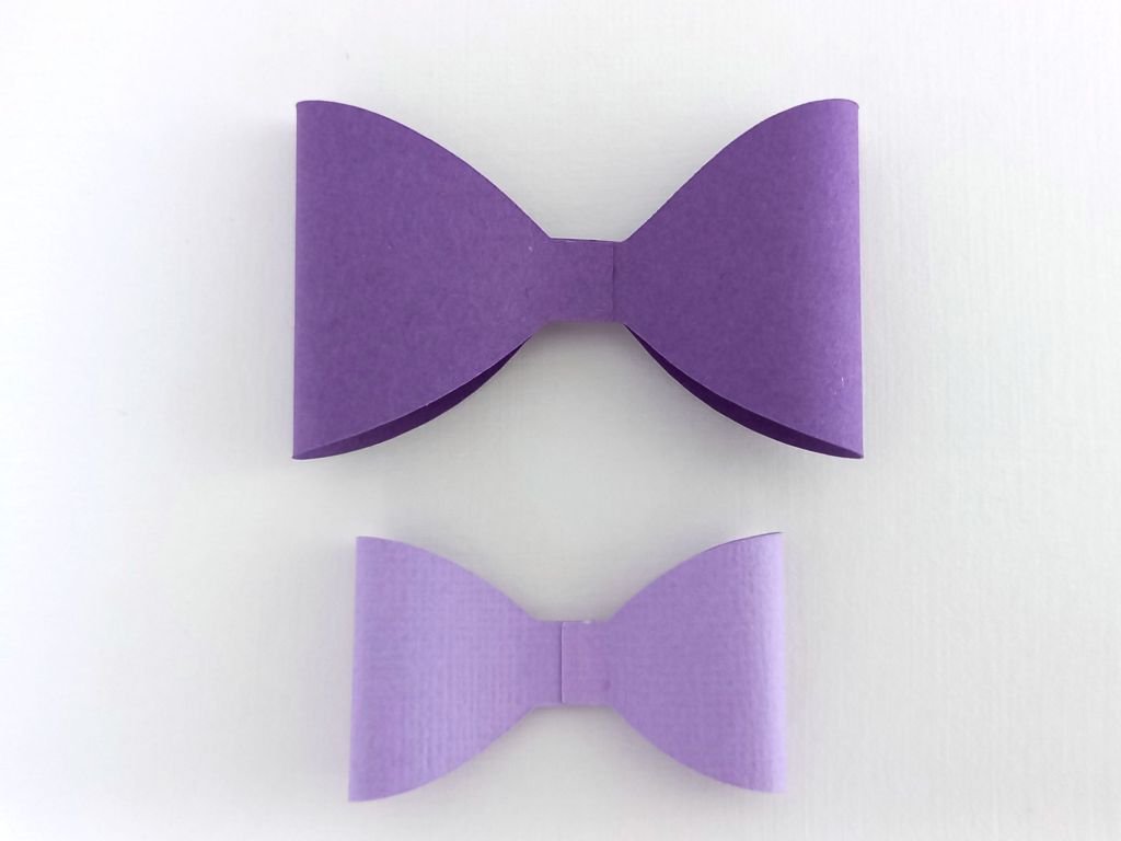 A black and purple bat bow made from textured cardstock that can be used on Halloween gift packaging or home decor