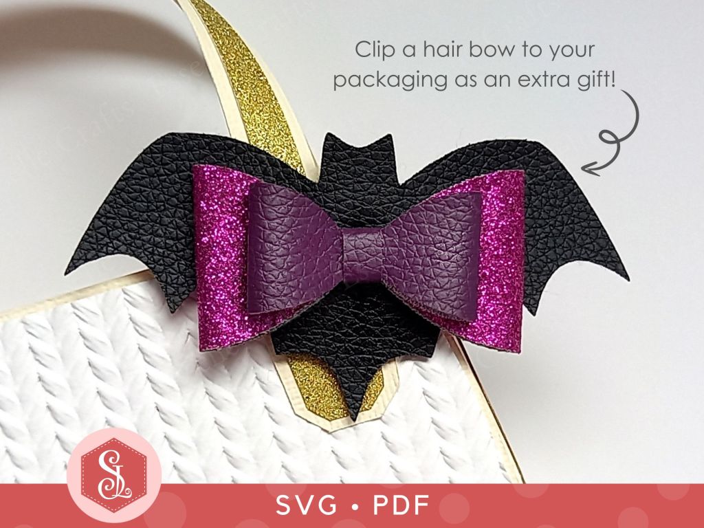 A black and purple bat bow made from faux leather and thin glitter fabric that can be used as a Halloween hair bow or a brooch