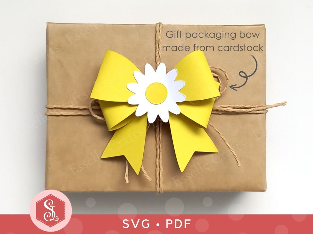 A papercraft gift bow made from yellow cardstock with a white and yellow paper daisy in the centre for adding to gift packaging