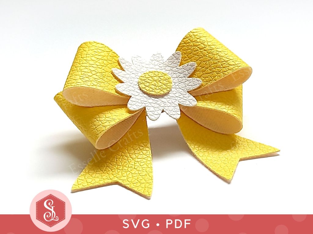 A hair bow made from yellow faux leather with a white and yellow faux leather daisy in the centre for adding to a hair clip or headband