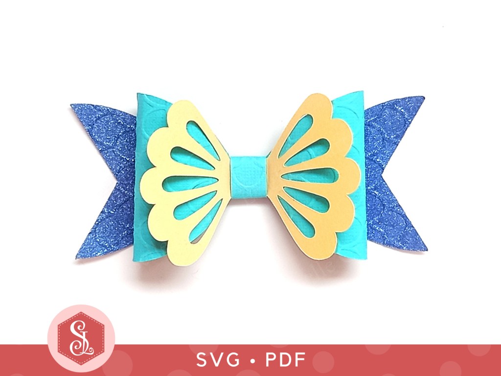 A mermaid gift bow made from blue glitter cardstock and teal and cream cardstock that can be used on gift packaging or home decor