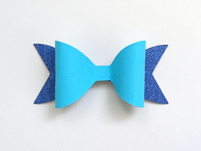 A mermaid gift bow made from blue glitter cardstock and teal and cream cardstock that can be used on gift packaging or home decor
