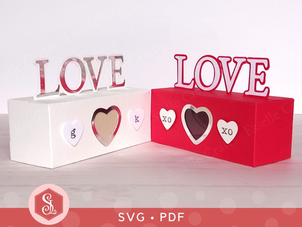 A red papercraft treat box for Valentine's day with the word LOVE on the top and decorated with paper hearts