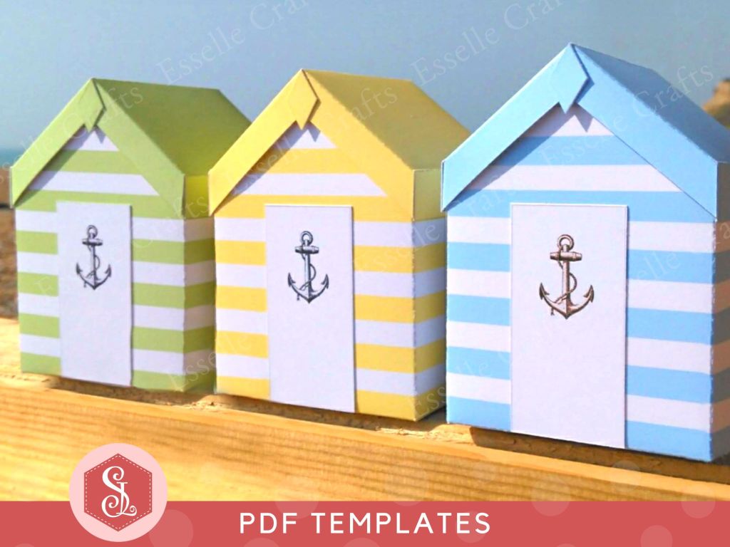 Three colourful papercraft gift boxes in the style of beach huts, each decorated with white stripes and a grey anchor on the door.