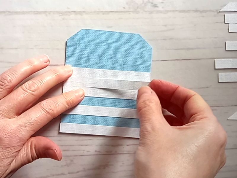A papercraft gift card holder in the style of a beach hut, decorated with blue and white stripes.