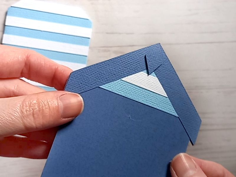 A papercraft gift card holder in the style of a beach hut, decorated with blue and white stripes.