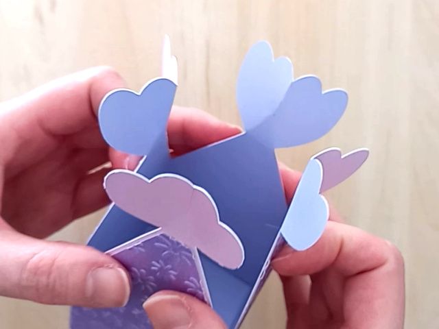 A papercraft favour box in the style of a flower made from lavender paper and closed with a satin ribbon