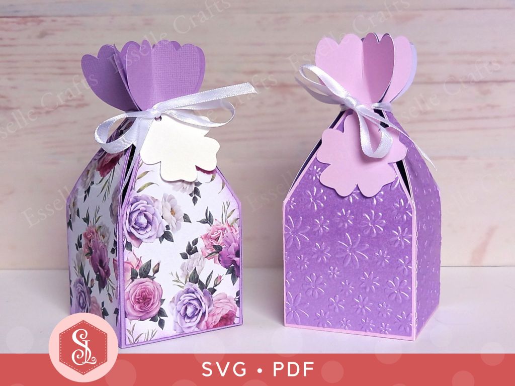 Two papercraft favour boxes in the style of a flower made from lavender paper and closed with a satin ribbon