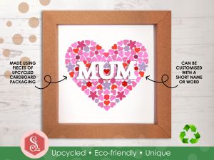 A pink mosaic heart design made from small pieces of upcycled paper packaging, framed in a square brown kraft card frame. The word MUM is displayed across the middle in white capital letters. 