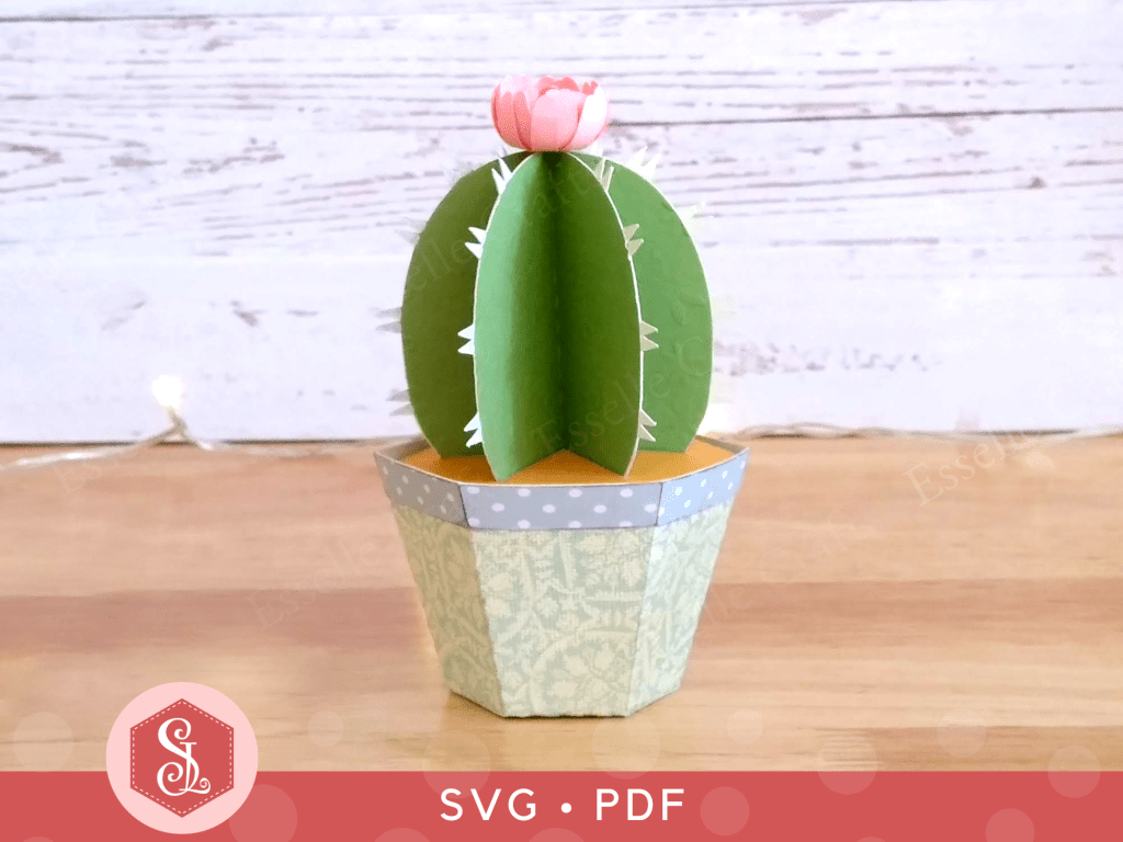 A papercraft favour box in the shape of a cactus in a plant pot with a pink paper flower on the top