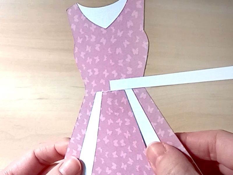 A papercraft gift card holder in the style of a vintage pink dress. It is decorated with white paper panels on the front.