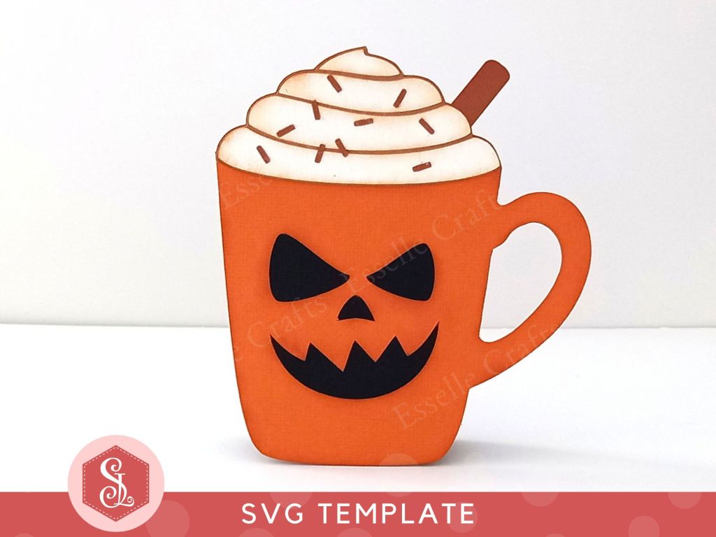 A papercraft gift card holder in the style of a pumpkin spice latte mug. It has a spooky black cut out face in the centre of the mug and is topped with white paper whipped cream, a brown paper cinnamon stick and dark brown paper sprinkles.